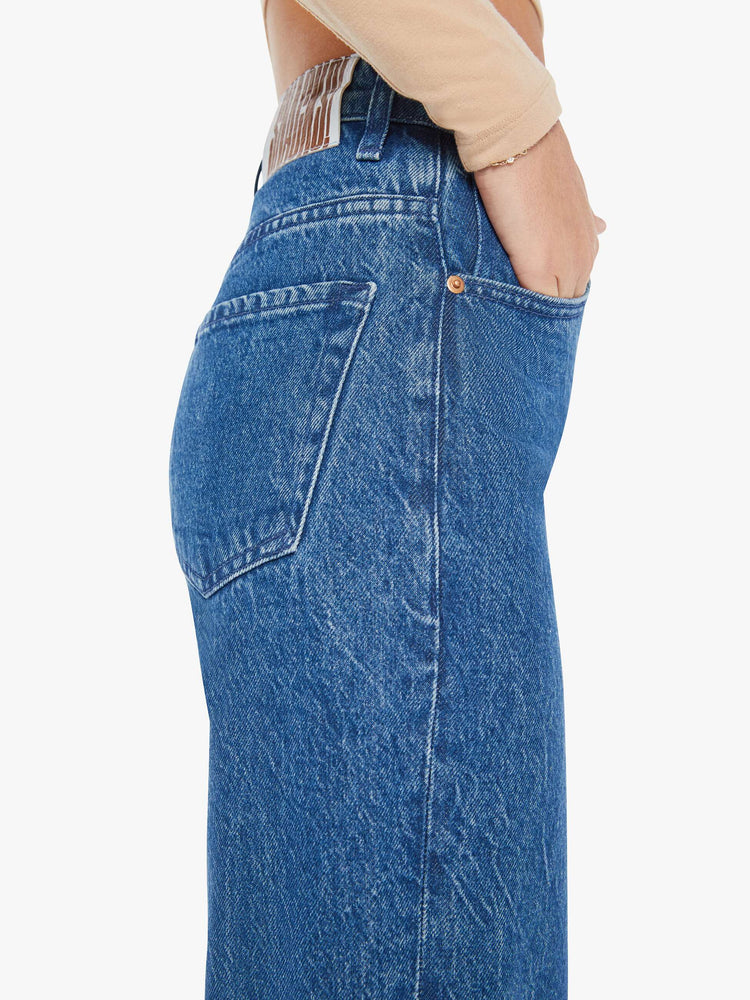 Side close up view of a womens medium blue wash jean featuring a high rise.