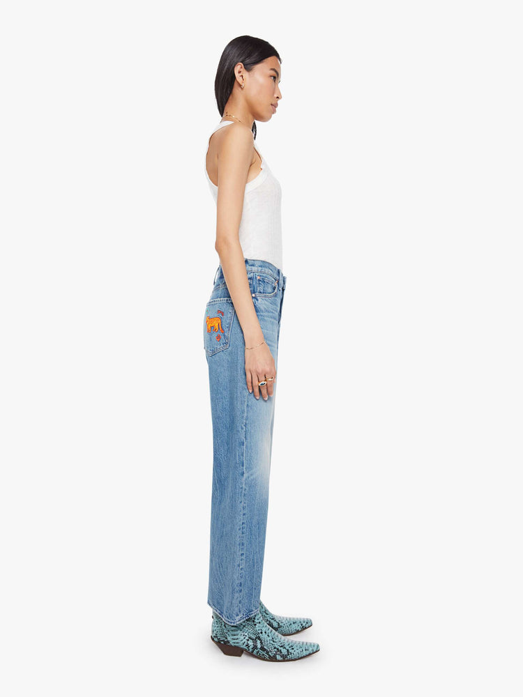 Side view of a woman in jeans designed to sit on the hips with a slouchy fit, a loose straight leg, zip fly and a 28.25-inch inseam with a clean hem.