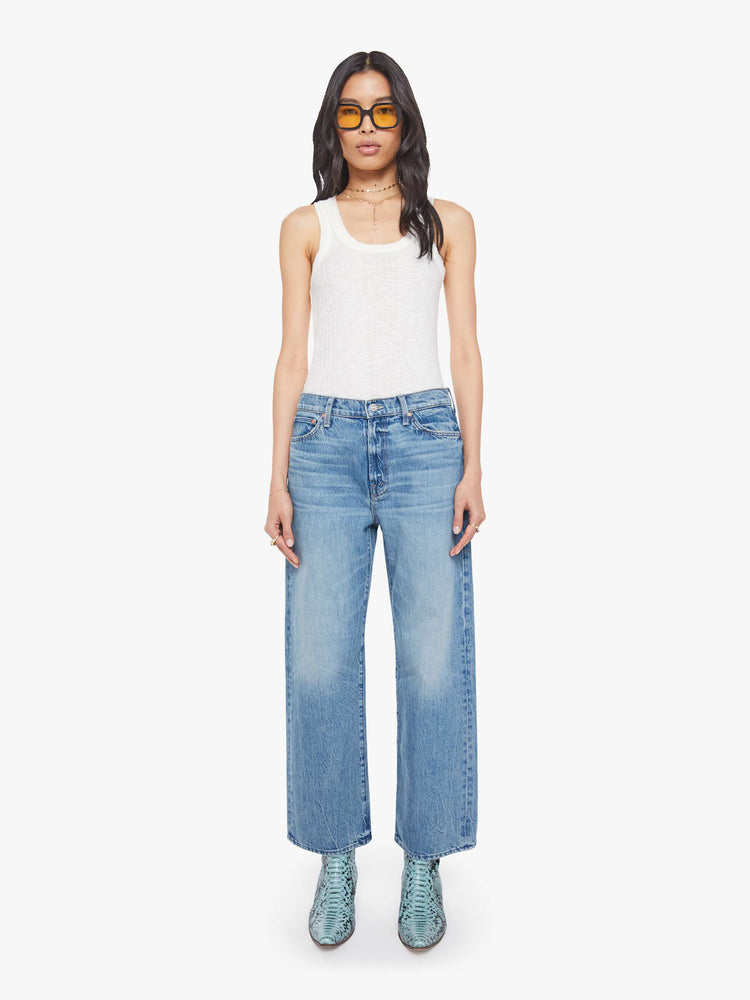 Front view of a woman in a mid blue jeans designed to sit on the hips with a slouchy fit, a loose straight leg, zip fly and a 28.25-inch inseam with a clean hem.