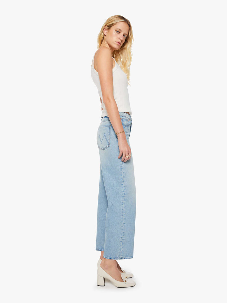 Side view of a woman in light blue jeans designed to sit on the hips with a slouchy fit, a loose straight leg, button fly and a 28.25-inch inseam with a clean hem.