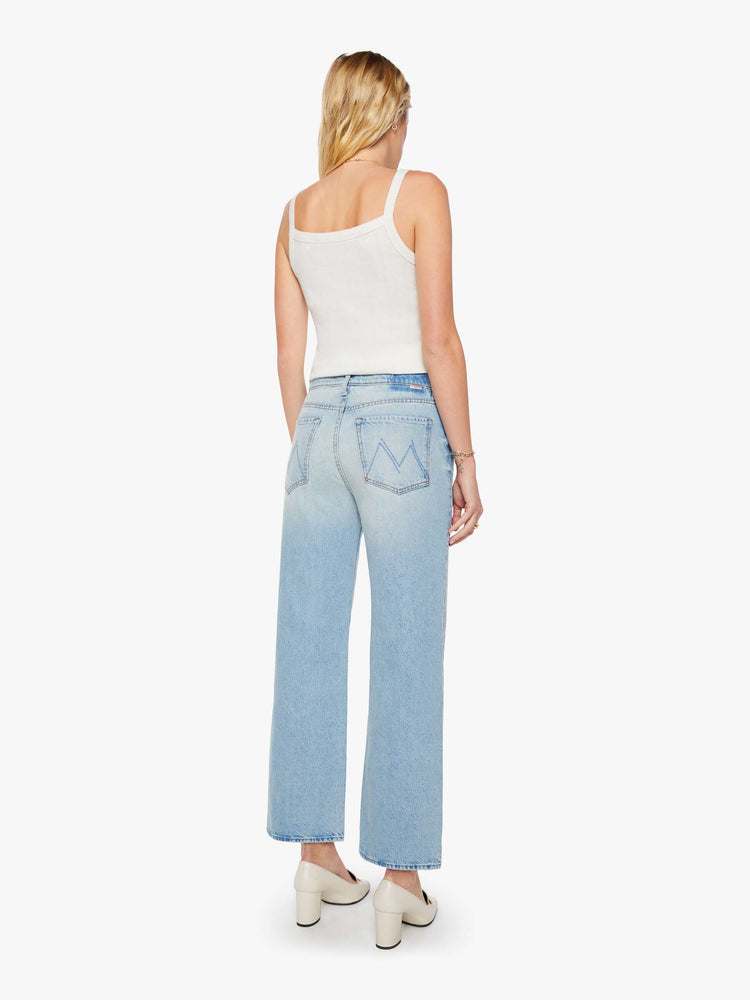 Back view of a woman in light blue jeans designed to sit on the hips with a slouchy fit, a loose straight leg, button fly and a 28.25-inch inseam with a clean hem.
