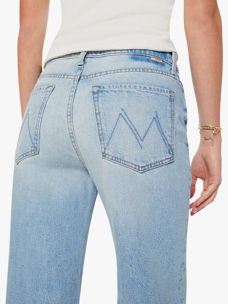 Close up view of a woman in light blue jeans designed to sit on the hips with a slouchy fit, a loose straight leg, button fly and a 28.25-inch inseam with a clean hem.