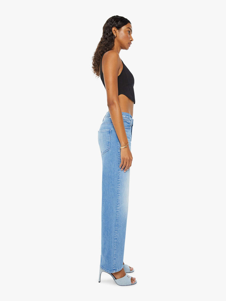 Side view of a woman in light blue loose straight leg jeans designed to sit lower on the hips with a clean hem and whiskering and fading at the knees.