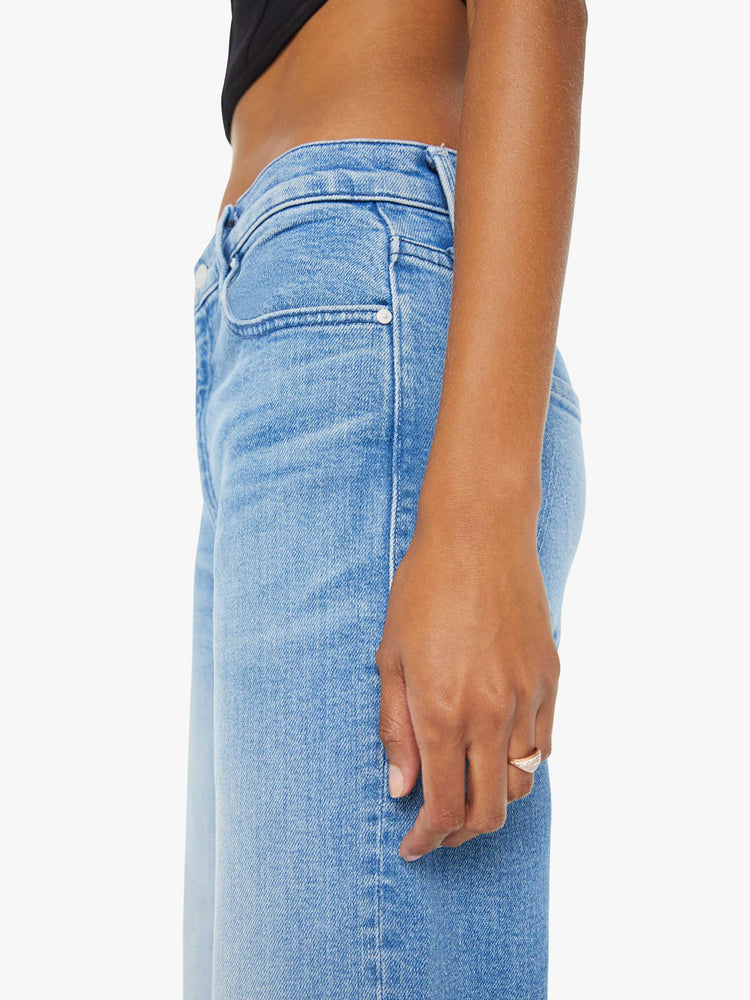 Swatch view of a woman in light blue loose straight leg jeans designed to sit lower on the hips with a clean hem and whiskering and fading at the knees.
