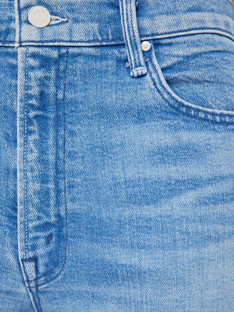 Detailed view of a woman in light blue loose straight leg jeans designed to sit lower on the hips with a clean hem and whiskering and fading at the knees.