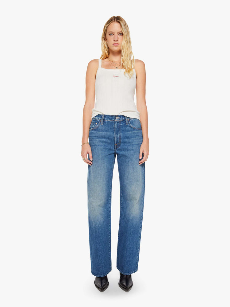 Front view of a woman in a med blue jeans designed to sit on the hips with a slouchy fit, a loose straight leg, button fly and a 28.25-inch inseam with a clean hem. 