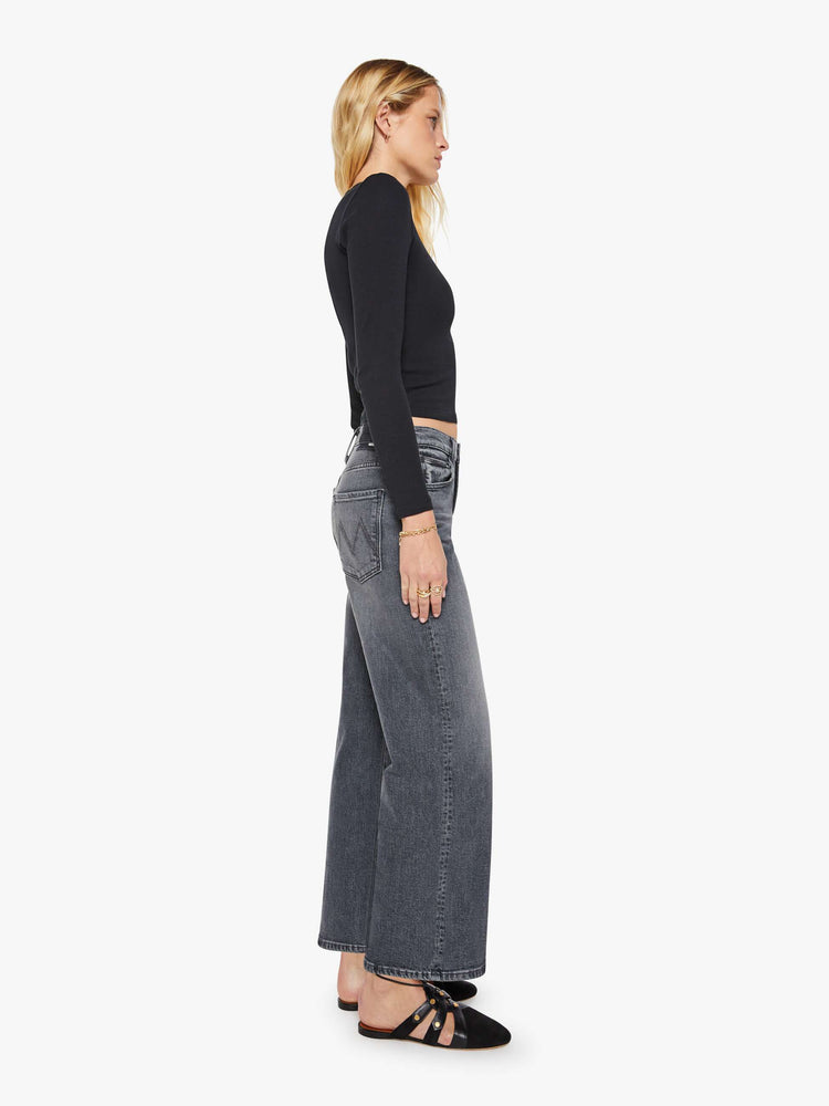 Side view of a woman in a dark grey Jeans designed to sit on the hips with a slouchy fit, a loose straight leg, button fly and a 28.25-inch inseam with a clean hem.