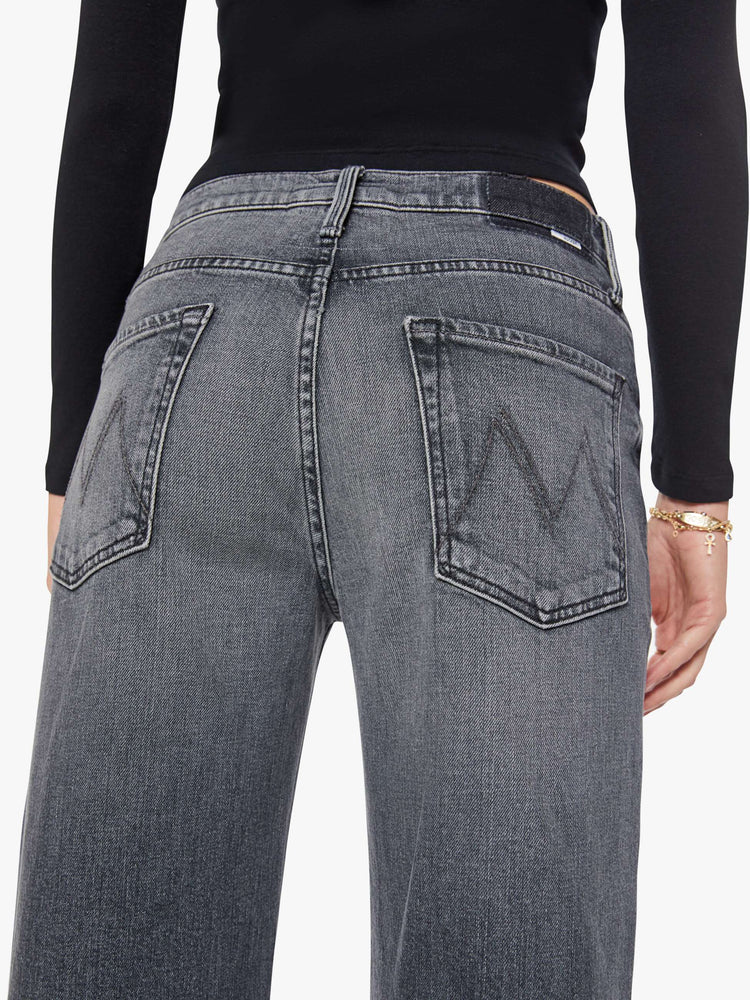Close up view of a woman in a dark grey Jeans designed to sit on the hips with a slouchy fit, a loose straight leg, button fly and a 28.25-inch inseam with a clean hem.