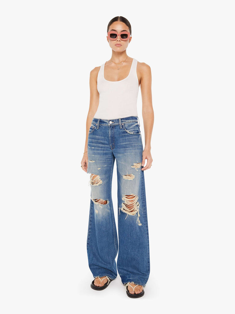 Front view of a womens medium blue wash jean featuring a low rise, wide leg, and distressed details throughout.