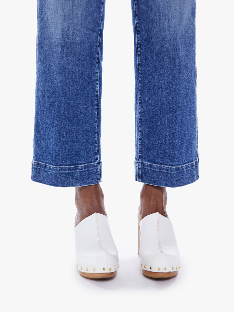 Hem close up view of a woman Wide-leg jeans with a high rise, button fly, cinched waist and an ankle-length inseam with a thick hem in a mid-blue wash.