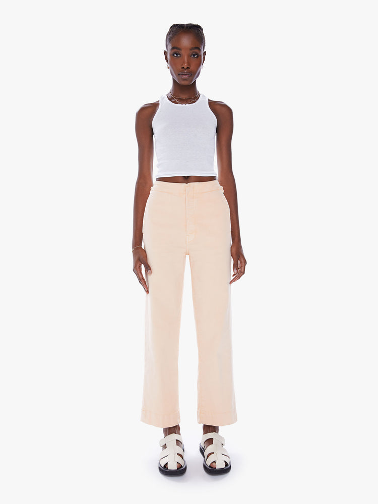 Front view of a woman wide-leg pants with a high rise, button fly, cinched waist and an ankle-length inseam with a thick hem in a peach hue.