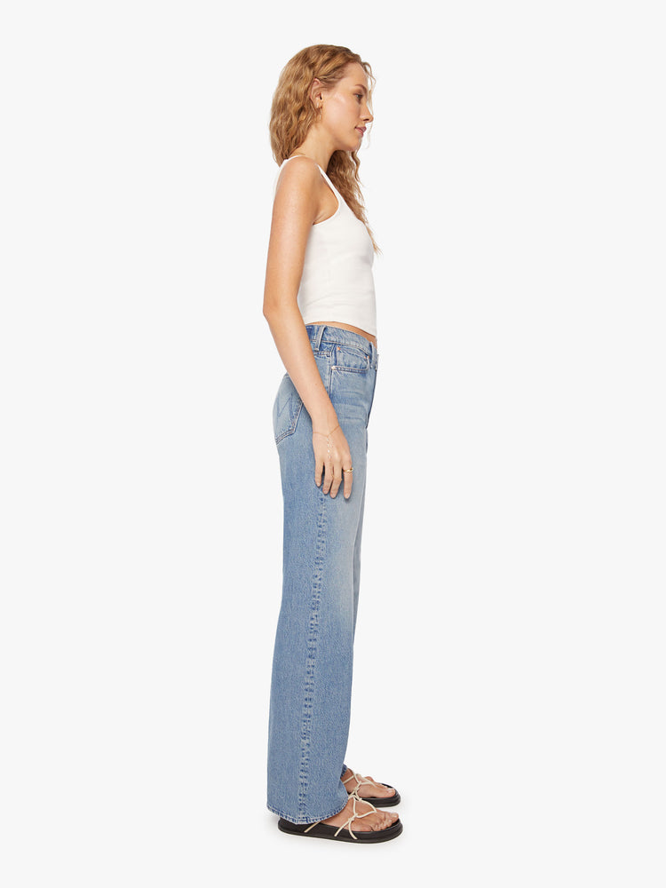 Side view of a womens light blue jean featuring a high rise and a relaxed wide leg.