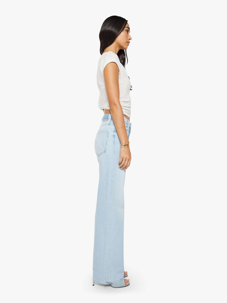 Side view of a woman in a light blue jeans designed to sit on the hips with a zip fly, slouchy fit, loose straight leg and a 32-inch inseam with a clean hem.