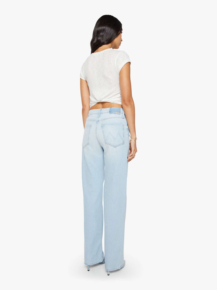 Back view of a woman in a light blue jeans designed to sit on the hips with a zip fly, slouchy fit, loose straight leg and a 32-inch inseam with a clean hem.