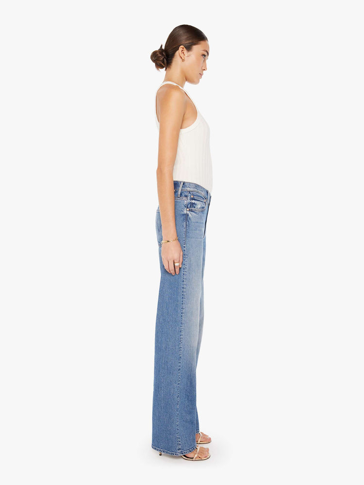 Side view of a medium blue wash jean featuring a relaxed mid rise, a wide leg, and a full length clean hem.