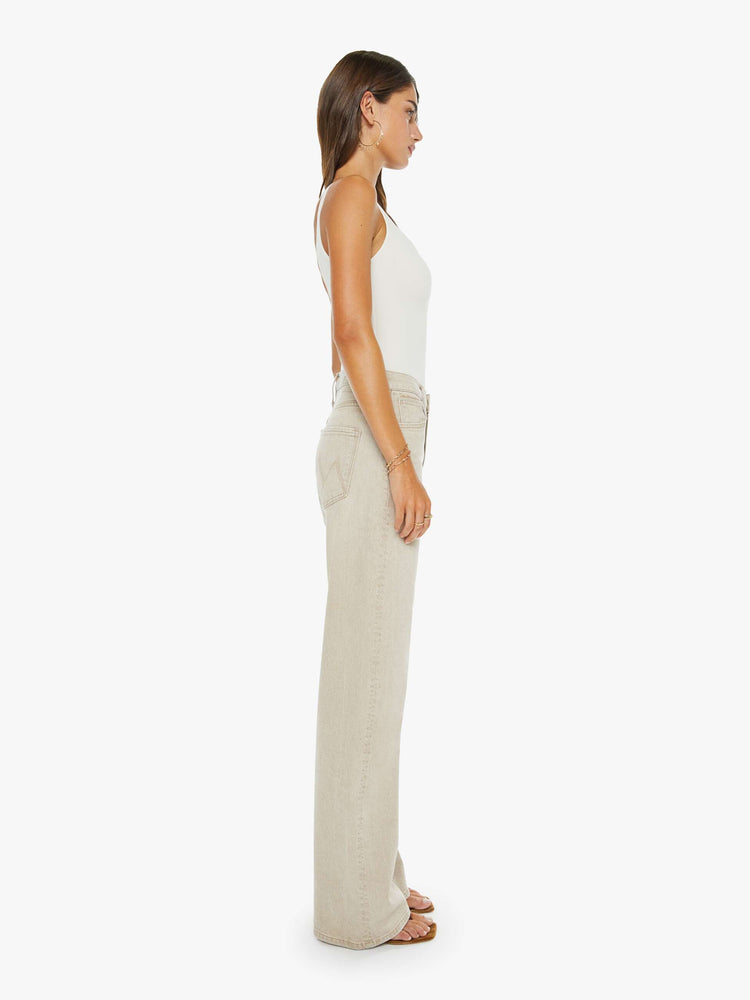 Side view of a woman in a faded khaki with tan stitching jeans designed to sit on the hips with a zip fly, slouchy fit, loose straight leg and a 32-inch inseam with a clean hem.
