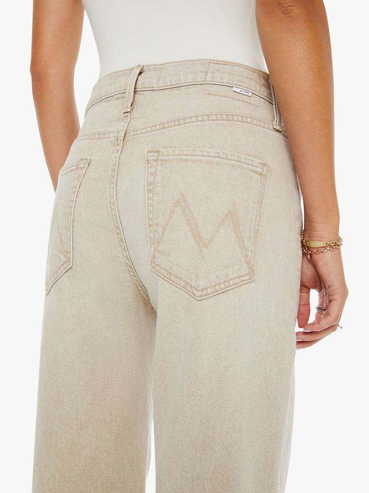 Close up view of a woman in a faded khaki with tan stitching jeans designed to sit on the hips with a zip fly, slouchy fit, loose straight leg and a 32-inch inseam with a clean hem.