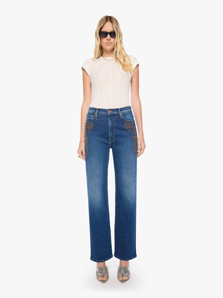 Front view of a woman in a med blue jeans designed to sit on the hips with a zip fly, slouchy fit, loose straight leg and a 32-inch inseam with a clean hem.