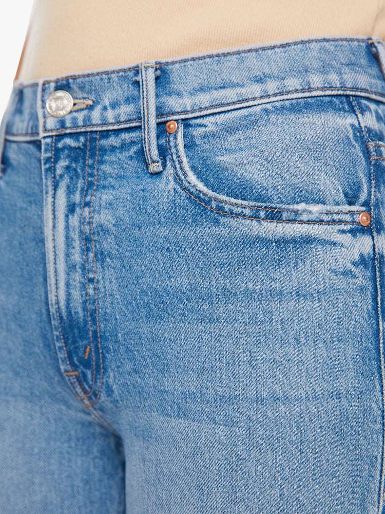 Close up waist view of a woman mid-rise bootcut has a 28.25-inch inseam and a clean hem in a vintage blue wash.