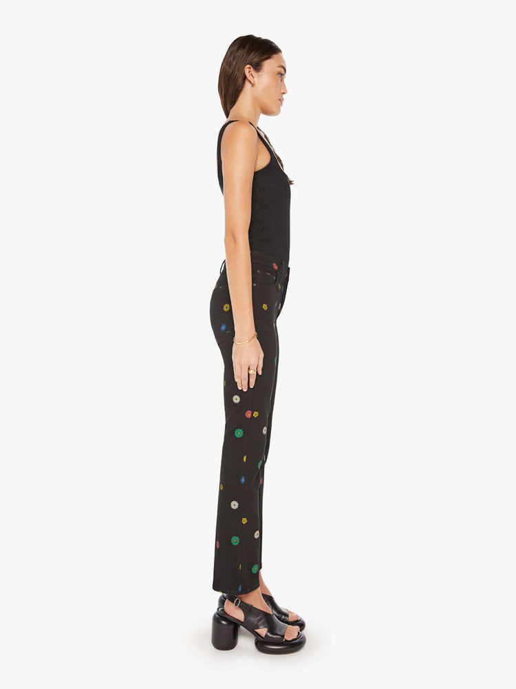 Side view of a woman high-rise bootcut has a 28.25-inch inseam and a clean hem in a black with flowers throughout.