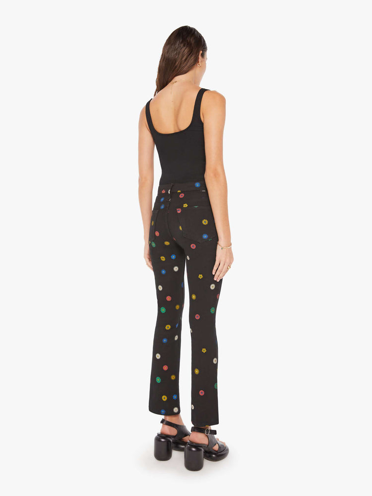 Back view of a woman high-rise bootcut has a 28.25-inch inseam and a clean hem in a black with flowers throughout.