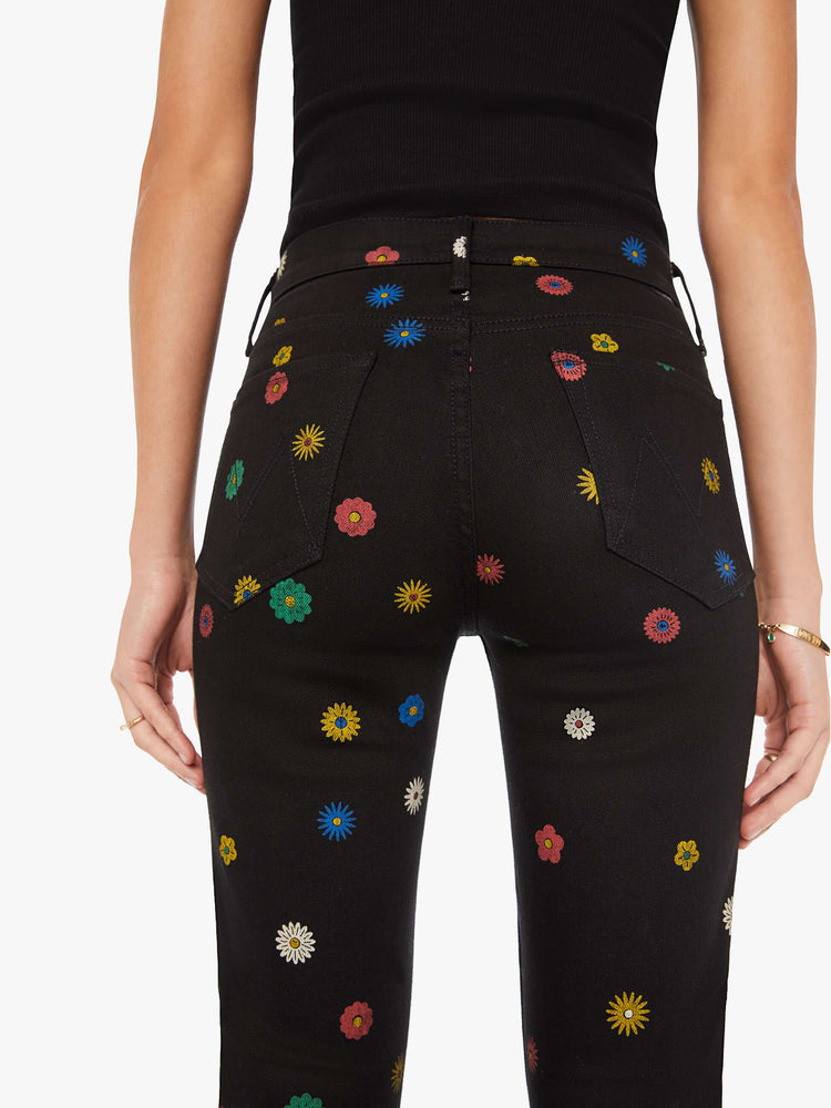 Close up view of a woman high-rise bootcut has a 28.25-inch inseam and a clean hem in a black with flowers throughout.