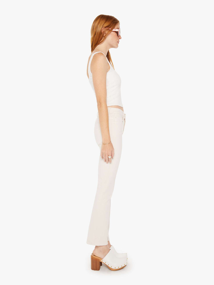 Side view of a woman light khaki cream colored high-rise bootcut has a 28.25-inch inseam and a clean hem pant.