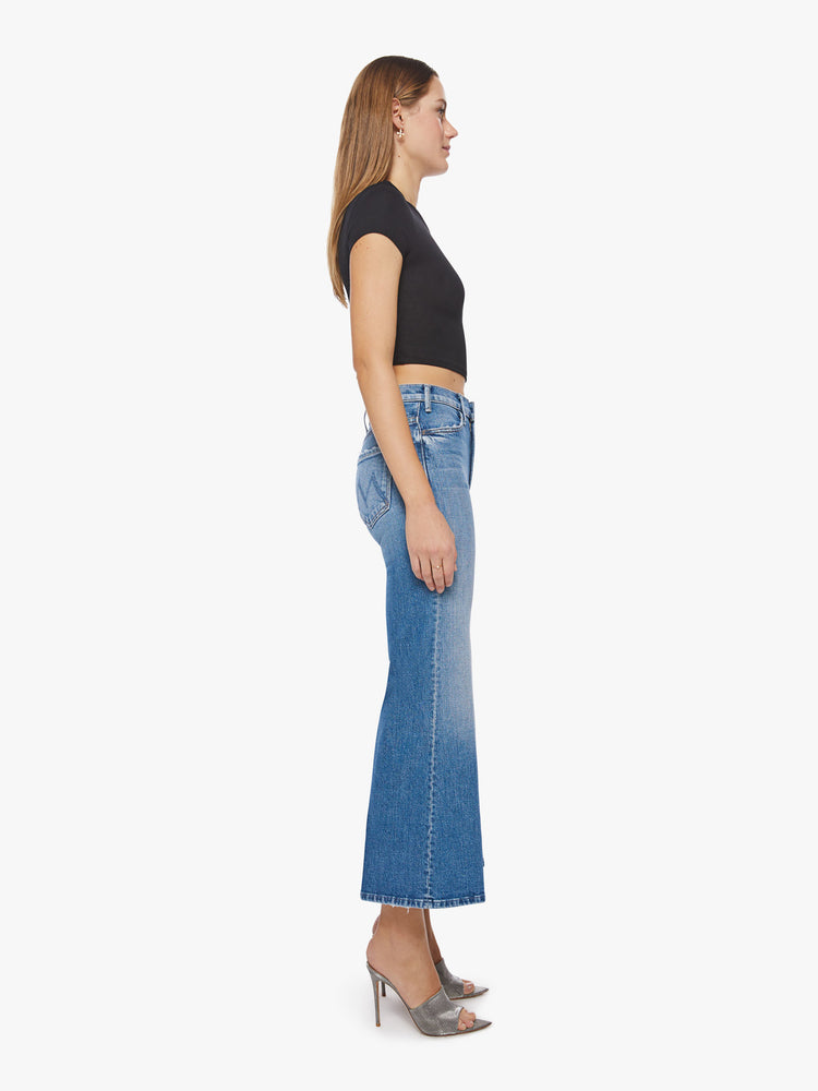 Side view of a woman wide-leg jeans with a high rise, ankle-length inseam and a clean hem in a light blue wash.