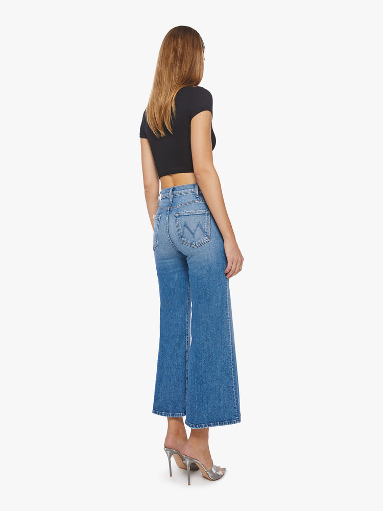 Back view of a woman wide-leg jeans with a high rise, ankle-length inseam and a clean hem in a light blue wash.