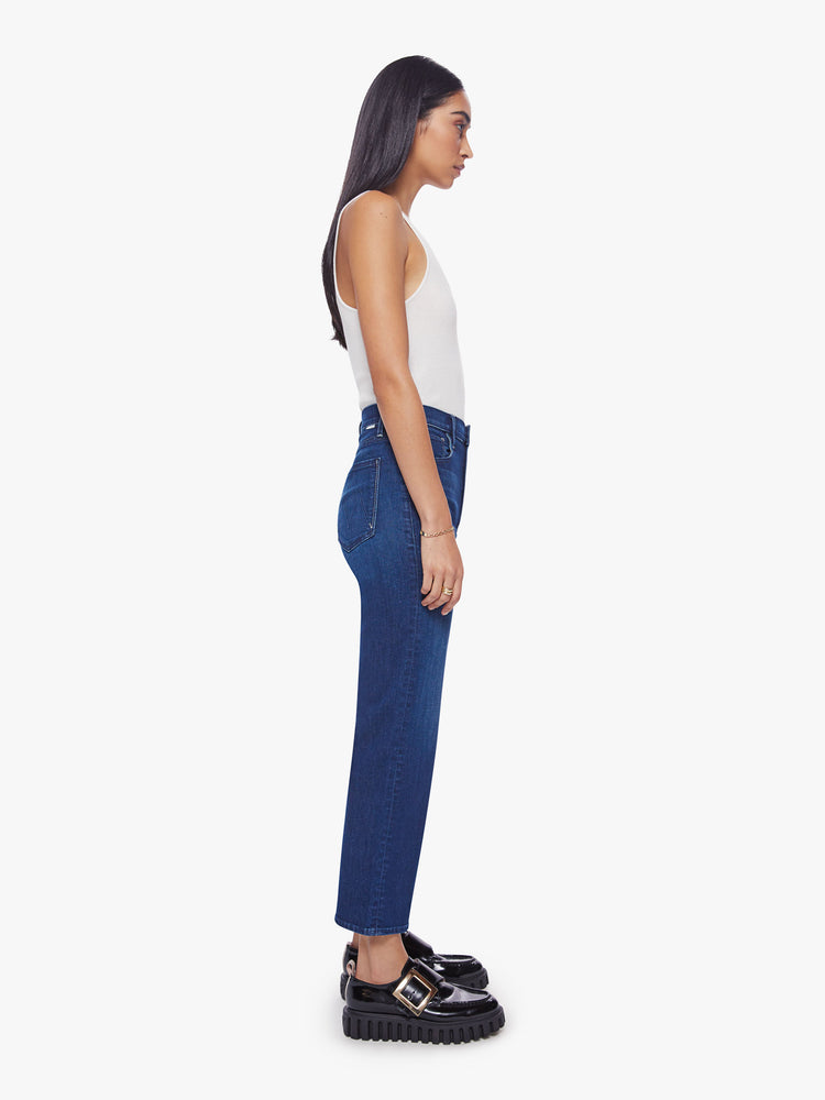 Side view of a woman high-waisted jeans with a wide straight leg, zip fly and clean ankle-length inseam in dark blue wash.