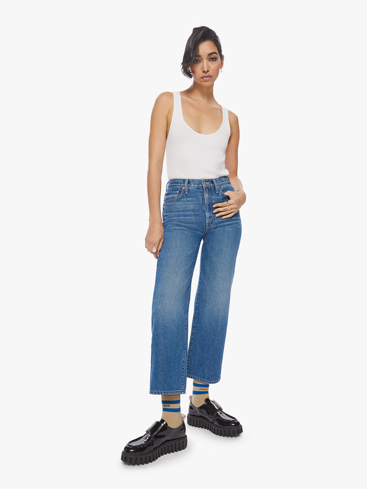 Front view of a woman high waisted jean with a wide straight leg, zip fly and clean ankle-length inseam in a med blue wash with studded text on the back.