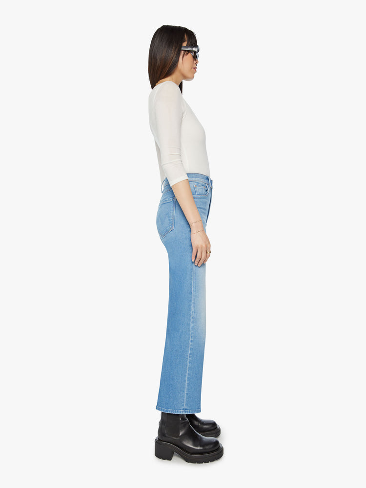 Side view of a woman high waisted jeans with a wide straight leg, zip fly and clean ankle-length inseam in a light blue wash.
