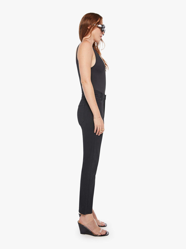 Side view of a woman in a black high-waisted straight leg with an ankle-length inseam and a clean hem.