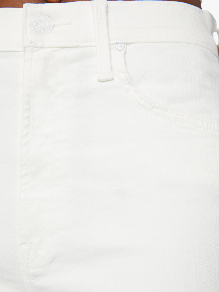 Swatch close up view of a woman wearing a high waisted straight leg jean with a clean ankle length hem in a white denim.