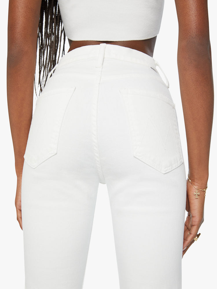 Close up back view of a woman wearing a high waisted straight leg jean with a clean ankle length hem in a white denim.