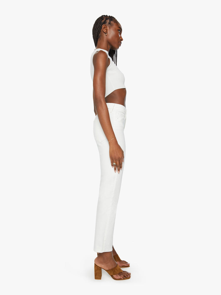 Side view of a woman wearing a high waisted straight leg jean with a clean ankle length hem in a white denim.