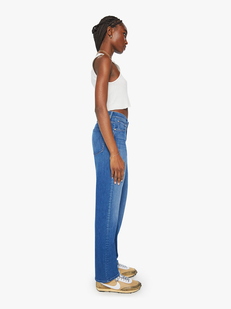 Side view of a woman mid rise straight-leg jeans with a zip fly, 31-inch inseam and relaxed fit in a mid blue wash.