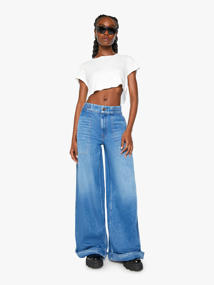 Front view of a women ultra wide-leg jeans are designed with a high rise, elastic waist, drop crotch, utility-inspired patch pockets and a long 32-inch inseam with a cuffed hem in a mid-blue wash.