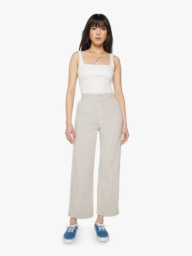 Front view of woman super high-waisted pants with a loose straight leg, zip fly, side slit pockets and an ankle-length inseam in an off white color.