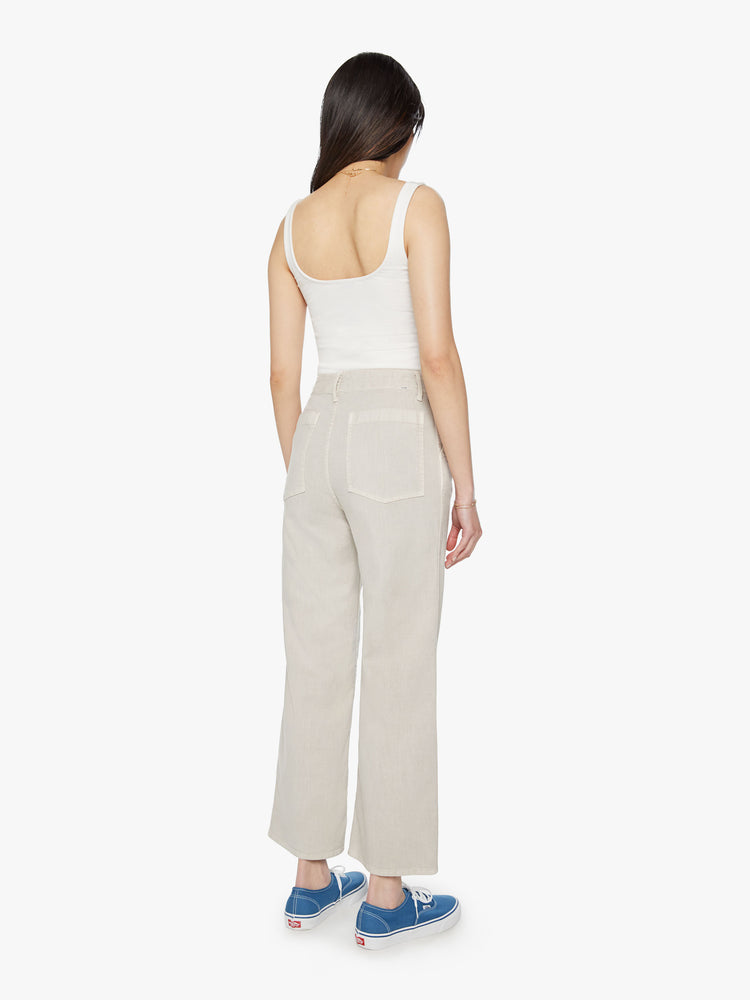 Back view of woman super high-waisted pants with a loose straight leg, zip fly, side slit pockets and an ankle-length inseam in an off white color.