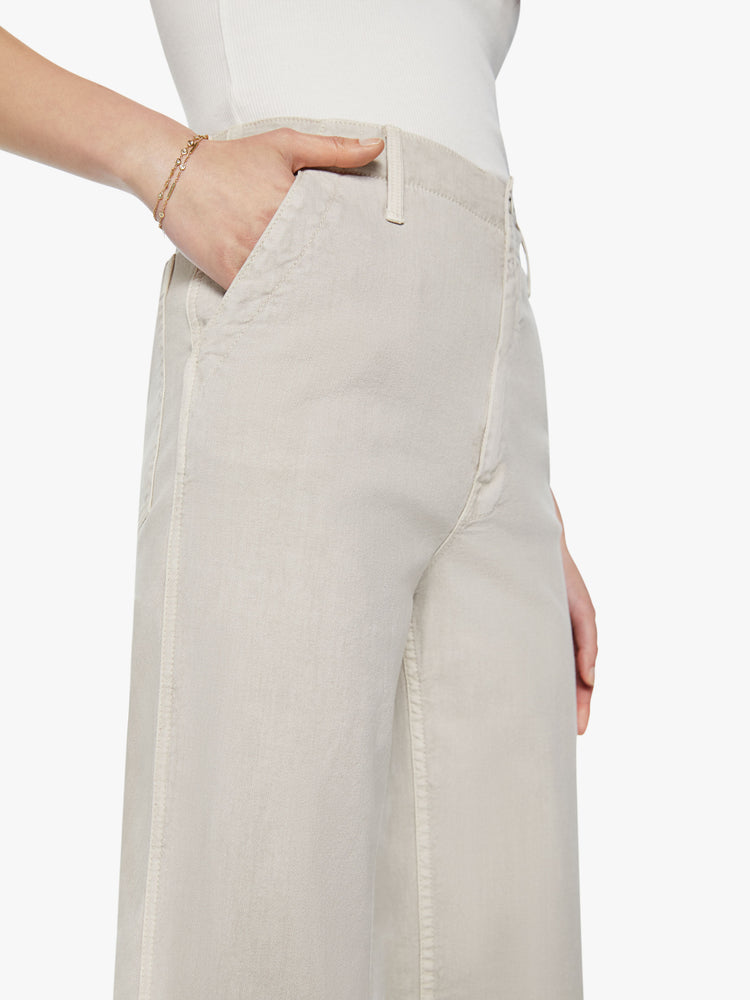 Waist view of woman super high-waisted pants with a loose straight leg, zip fly, side slit pockets and an ankle-length inseam in an off white color.