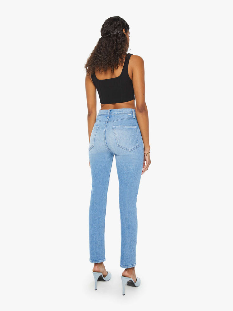 Back view of a woman in a light blue high-waisted straight leg jean with an ankle-length inseam, exposed button-fly and a clean hem.
