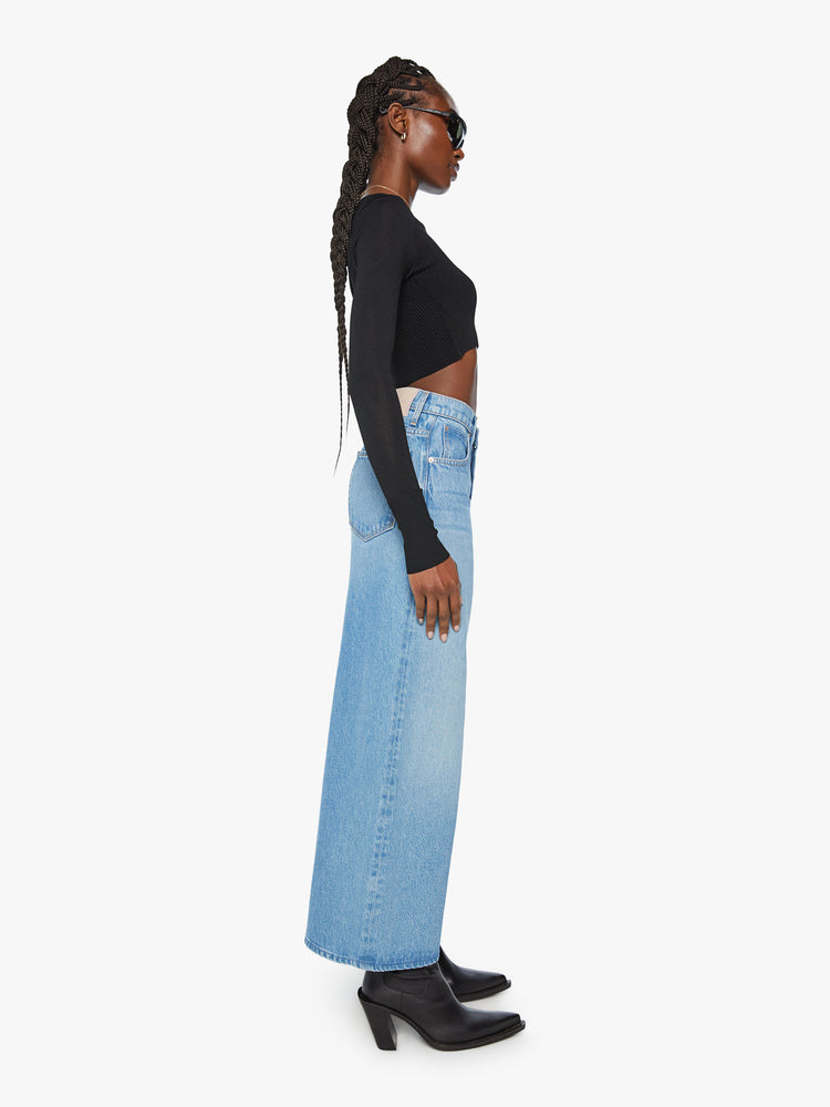 Side view of a woman super high-rise jeans feature a loose, wide leg and a cropped 26-inch inseam in a light blue wash.