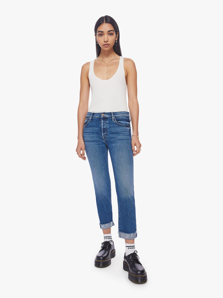 Front view of a woman button-fly jeans with a high rise and an ankle-length hem that's cuffed and frayed in a classic blue hue.