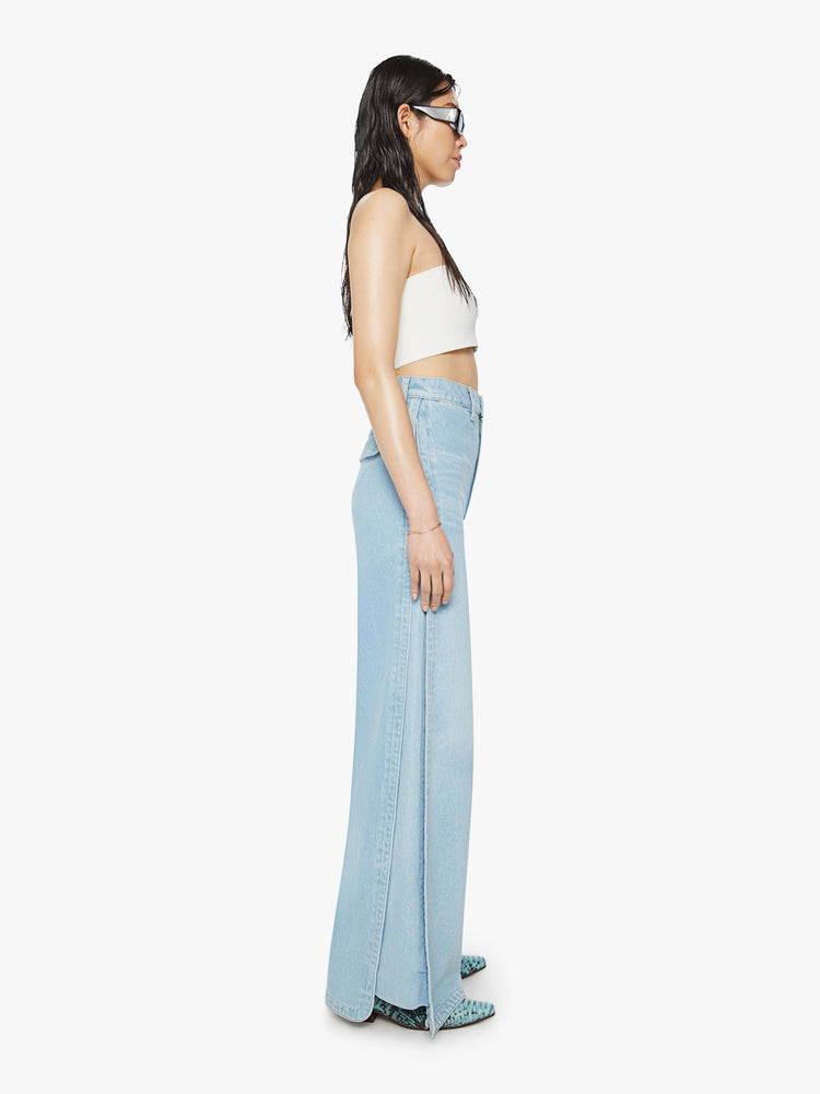Side view of a woman super high-waisted jeans feature an inset panel on the outer seam for an even wider fit and an extra-long 34-inch inseam in a light blue wash.