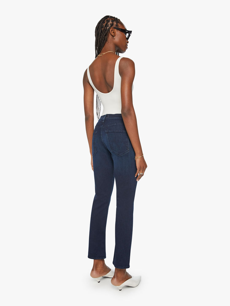 Back view of a woman dark blue mid-rise straight-leg jeans with an ankle-length inseam and a clean hem.