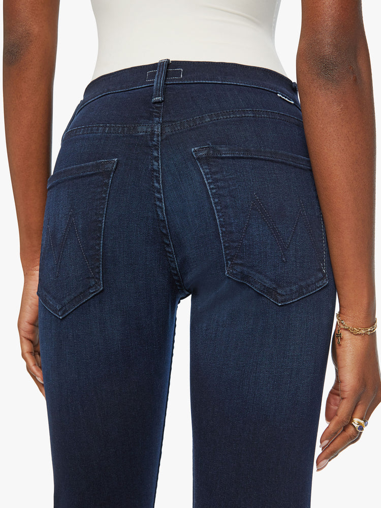 Back waist view of a woman dark blue mid-rise straight-leg jeans with an ankle-length inseam and a clean hem.