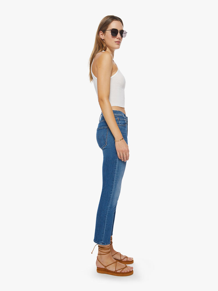 Side view of a woman mid-rise straight-leg jeans with an ankle-length inseam and a clean hem in a mid-blue wash.