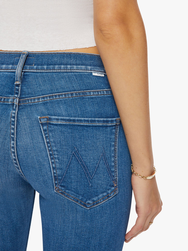 Close up back view of a woman mid-rise straight-leg jeans with an ankle-length inseam and a clean hem in a mid-blue wash.