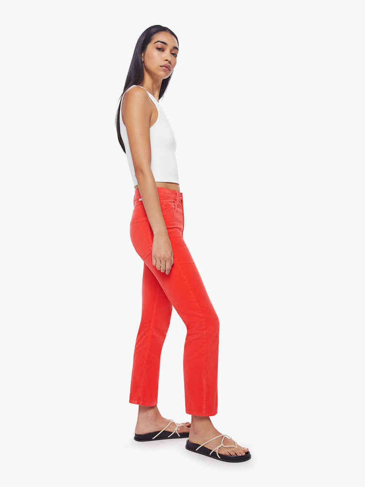 Side view of a woman mid-rise straight leg with an ankle-length inseam and a clean hem in a bright orange-red hue corduroy fabric.
